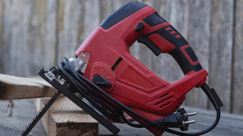 A red jigsaw leaning against wood