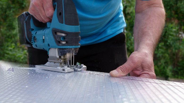 Man cutting metal with a blue jigsaw