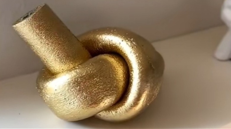 A gold pool noodle dupe of a Crate & Barrel sculpture