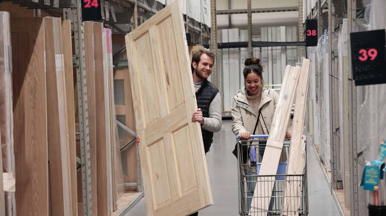 Couple buying builder-grade door and wood planks in store