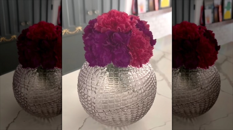 a glass candleholder repurposed as a vase holding pink and purple flowers