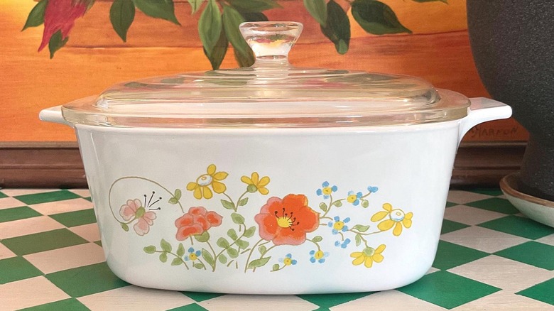 Vintage CorningWare Wildflower casserole dish with a lid on a green checkered surface