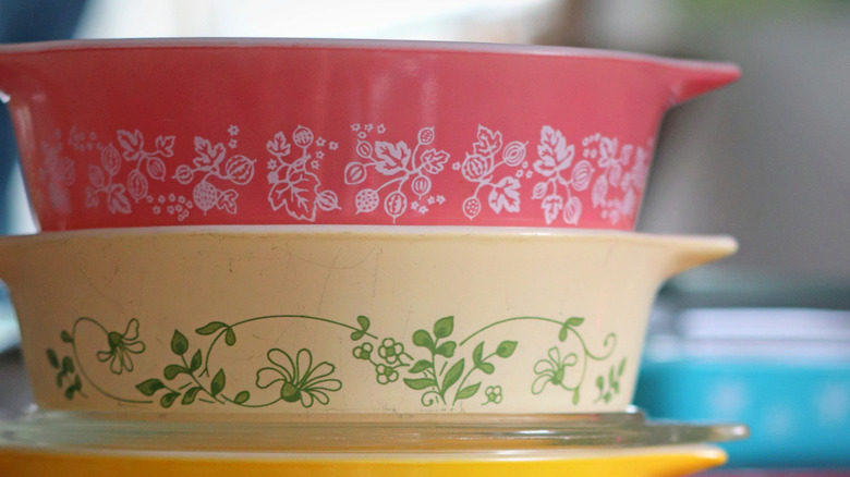 Collection of vintage CorningWare dishes in pink, white, and yellow