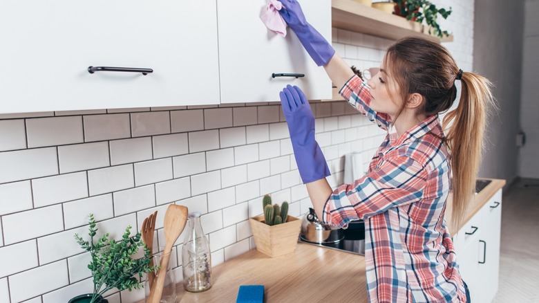 lady wiping kitchen cabinet