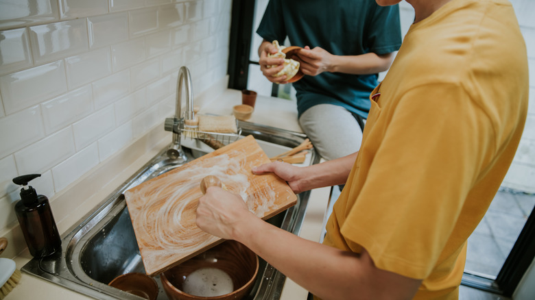 Man cleans cutting board in sink