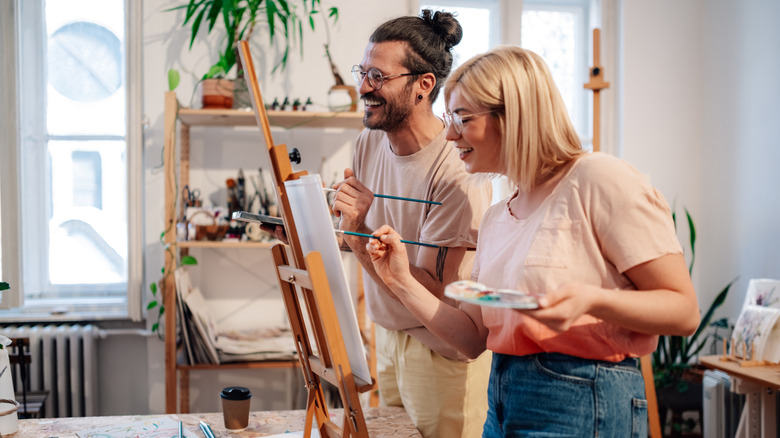 Two young people painting on a canvas