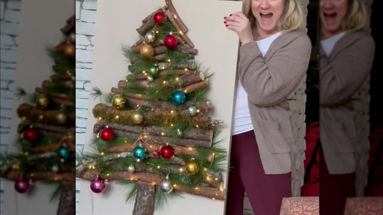 Woman holding a DIY Christmas Tree canvas made of sticks