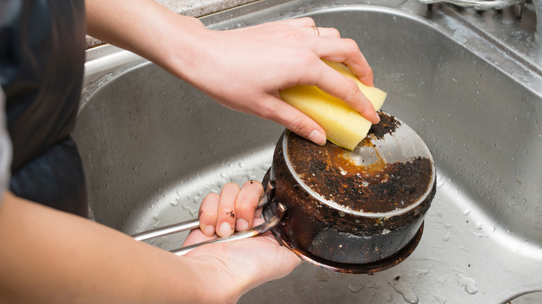 woman cleaning burnt pan