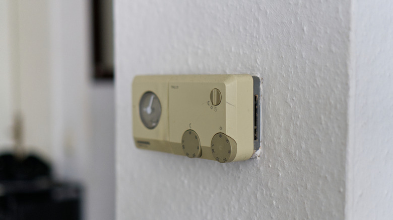 An old beige thermostat on the wall.