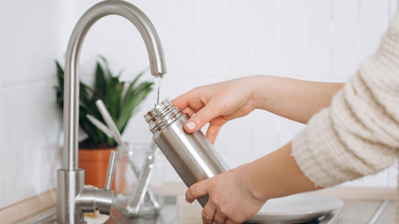 Woman drinking from metal bottle