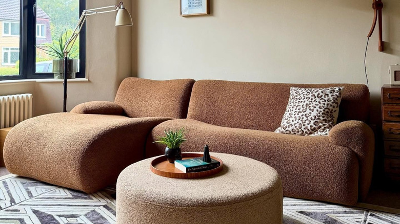 A brown boucle sofa in a natural organic shape with a leopard print cushion and matching table