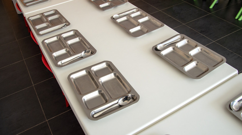 Empty silver food trays line a white table