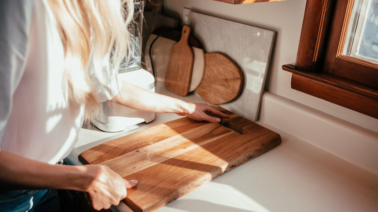 Woman organizing cutting boards against the wall