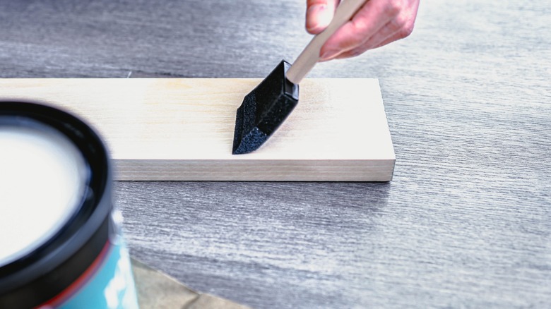 person painting wood plank