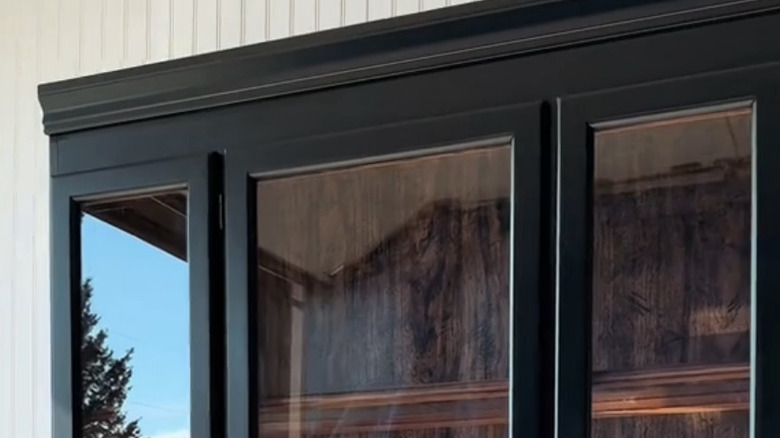 The corner of a modern black curio cabinet.