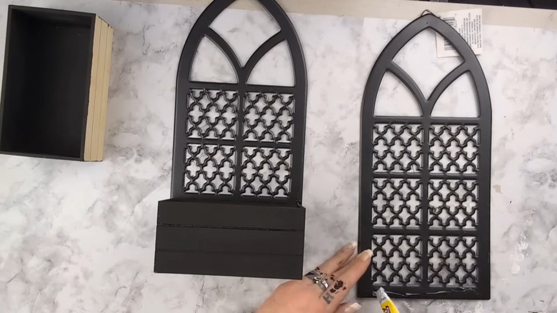 Person using glue gun to attach small crates to wooden arches