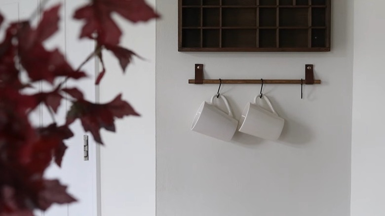 Two white mugs hang on a hanger made from Dollar Tree wares.
