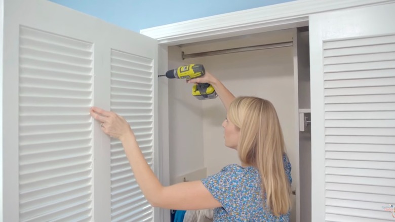 Woman screwing hinge onto closet door after turning bifold doors into french doors.