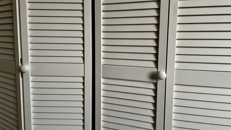 Old bifold closet doors not fully closed at the hinges.