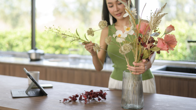 Woman putting cut flowers into a vase
