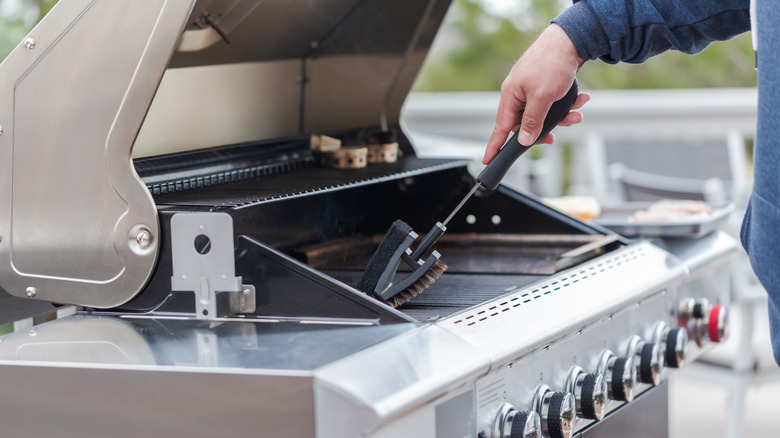 A person cleaning their grill with a brush