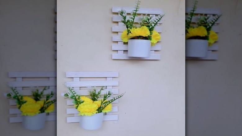 Two DIY wall planters made out of spray paint can lids and mini wood pallets.