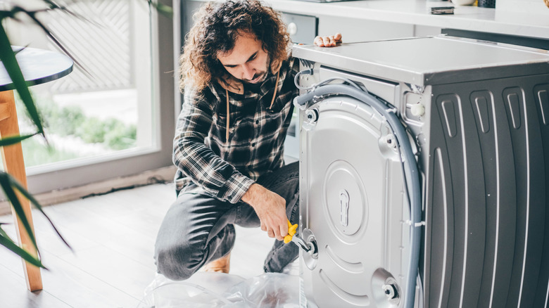 A man attempting to repair a washing machine