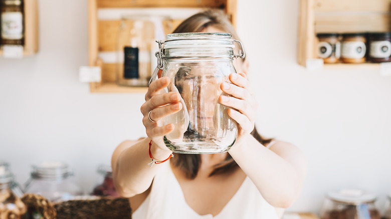 Woman holding a mason jar in front of her face