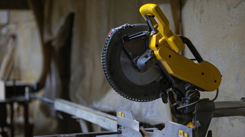A yellow miter saw currently not in use on what looks to be an in-home renovation site