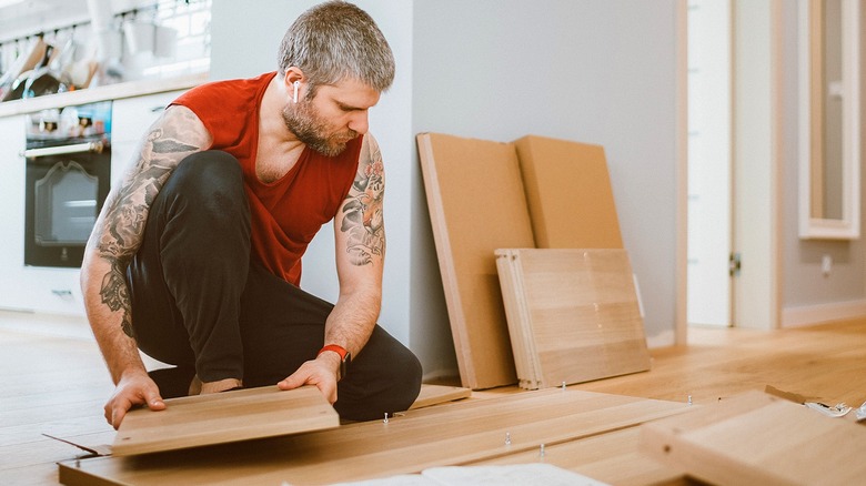 Person works on assembling table from a flatpack just outside a kitchen area