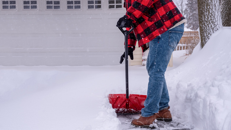 man shovels snowy driveway