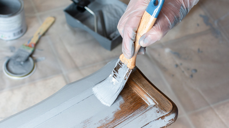 Person paints a drawer front a pale grey to create a unique vintage vibe.