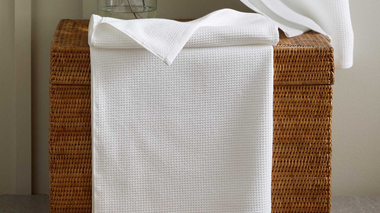 A Quince Turkish Waffle Terry Bath Towel hanging off of a woven basket