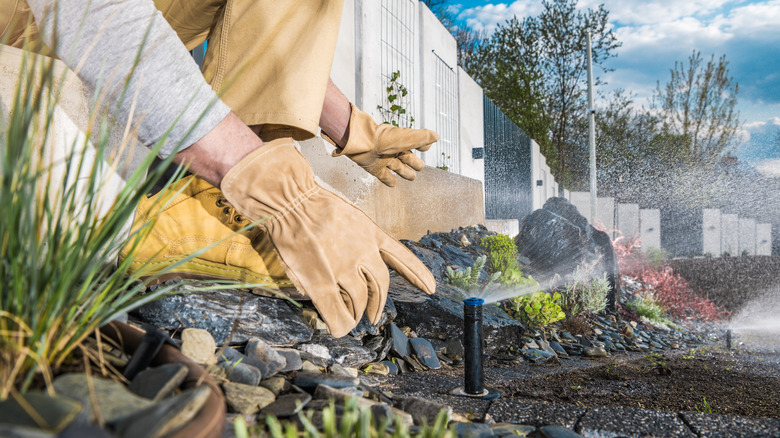 Gloved hand touching sprinkler head