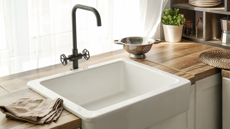 White ceramic kitchen sink in wood countertop