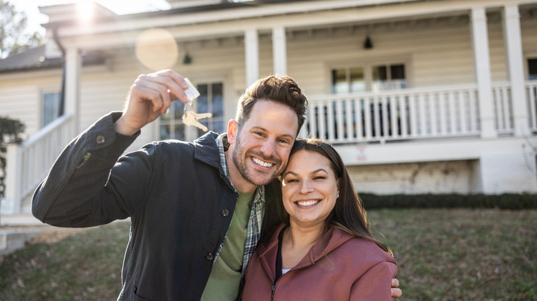 Happy couple in front of home with keys