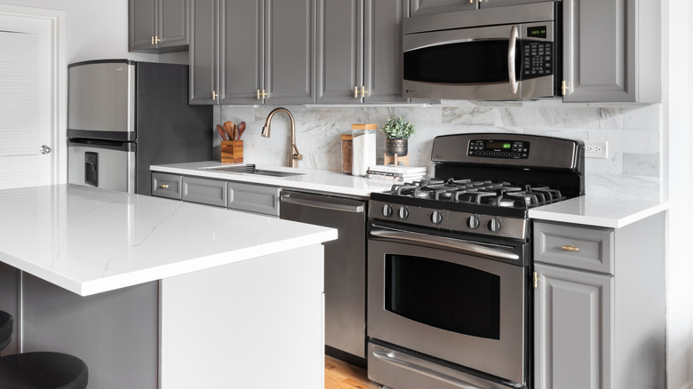 Grey and white kitchen with GE appliances including fridge, dishwasher, oven, and microwave