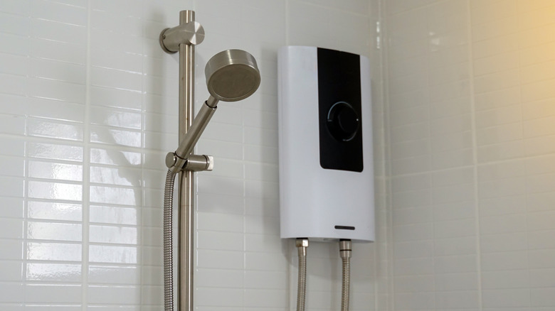 A small black and white water heater in a bathroom near shower