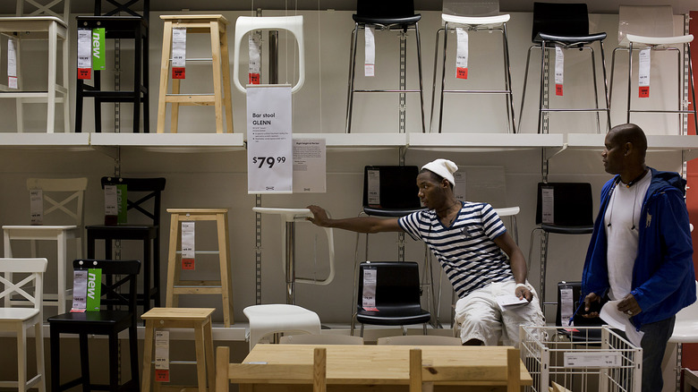 Male IKEA shoppers testing stools