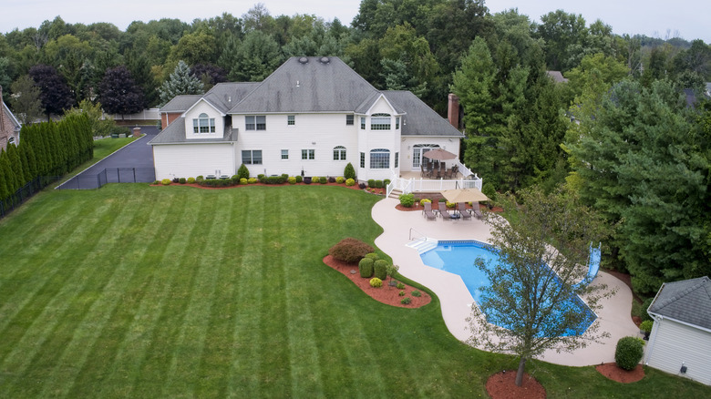 Striped lawn in backyard of white house with pool