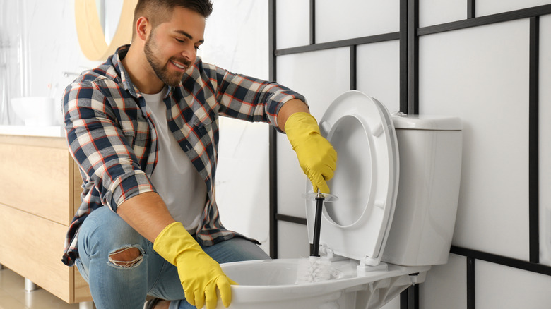 Man smiling while cleaning toilet