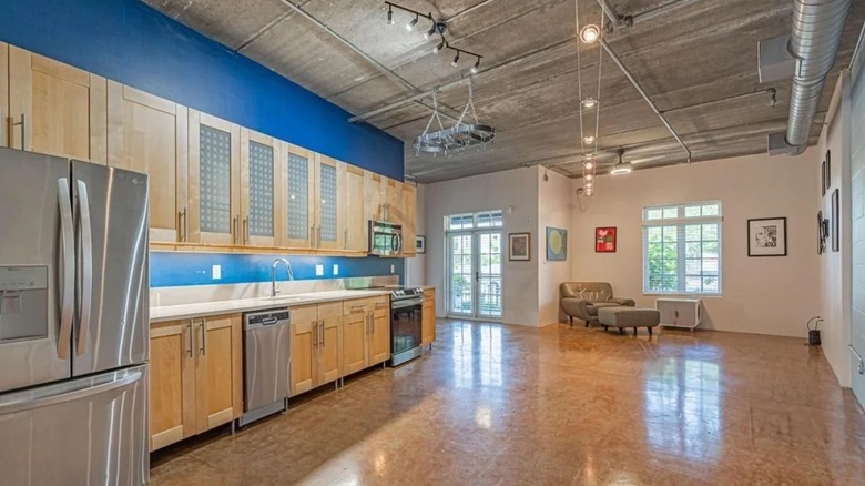 Industrial style loft apartment with white and blue walls, light-colored cabinets, and hard floor