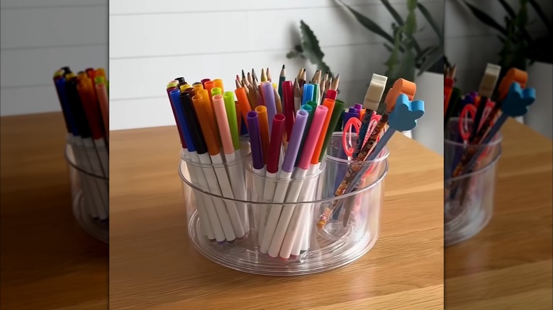 A clear lazy Susan with seven clear plastic cups glued inside for stationery