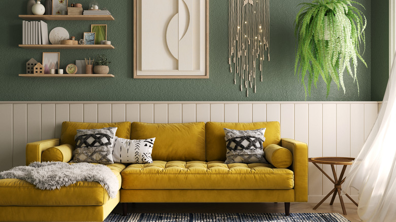 Cozy living room with a yellow sofa, wood paneling, and green walls