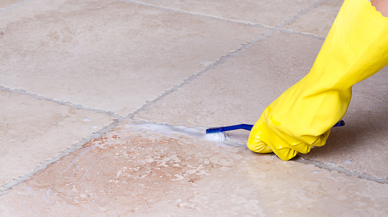 person cleaning grout with toothbrush