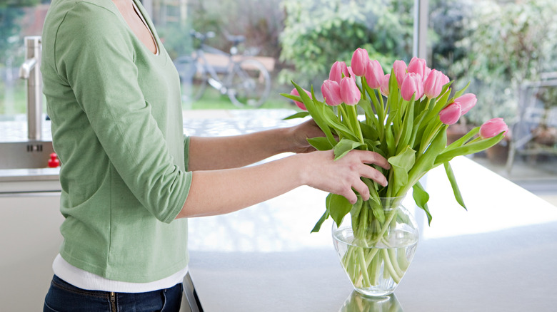 Person adding flowers to vase
