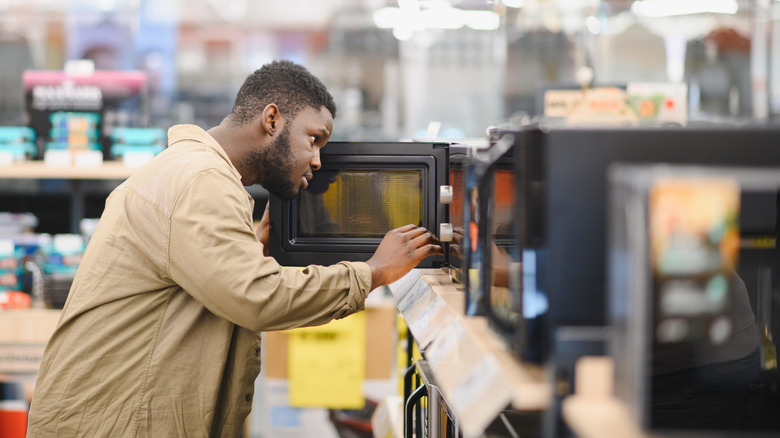 A man inspecting a microwave on a store shelf