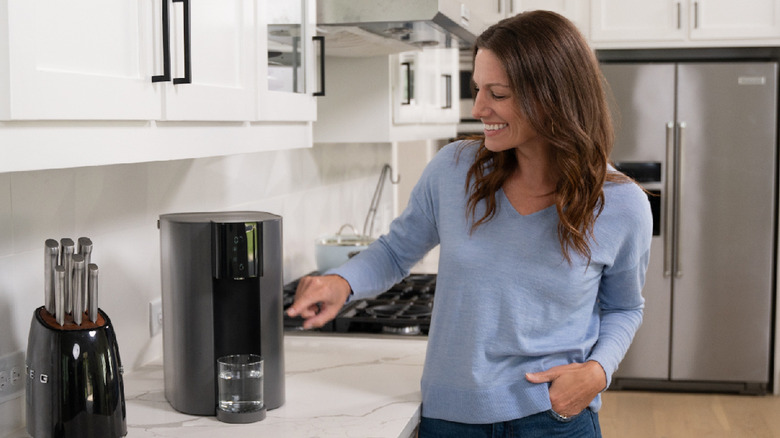 Woman smiling using Waterdrop Filter's countertop dispenser