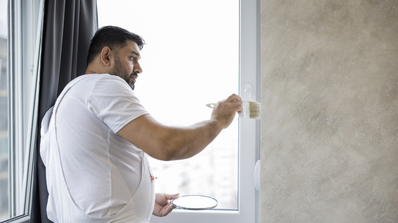 Person painting around a window