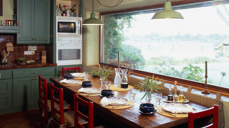 Wood dining table surrounded by red chairs in a retro room
